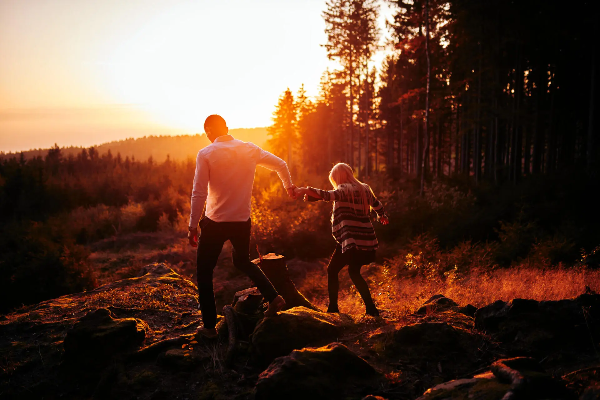 Paar läuft über Felsen im Sonnenuntergang